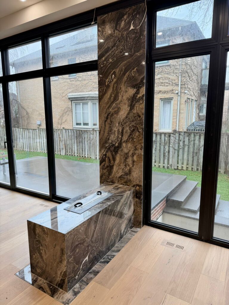 Custom stone fireplace with luxury marble feature wall and modern linear fire feature, designed and installed by ECCO Stone Works in Toronto GTA.