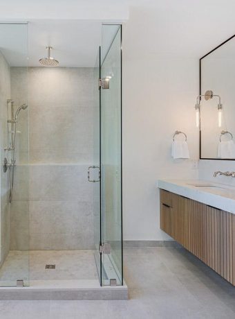 Modern bathroom with custom floating vanity, quartz countertop, and frameless glass shower featuring elegant stone finishes and minimalist design.